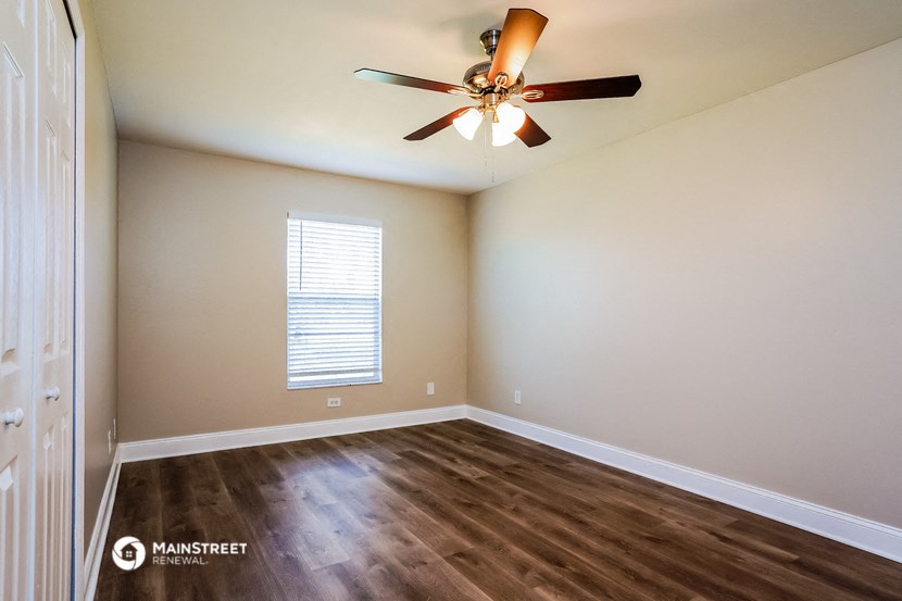 an empty living room with a ceiling fan