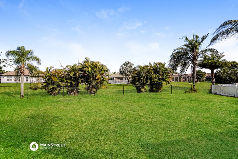 a large yard with palm trees and a fence