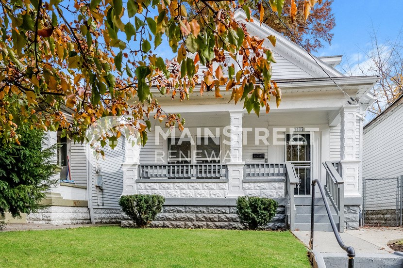 a white house with a front porch and a tree