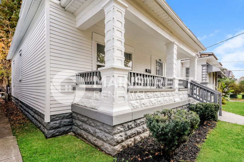 a large white house with a porch and a stone retaining wall