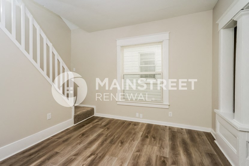 a renovated living room with hardwood floors and a staircase