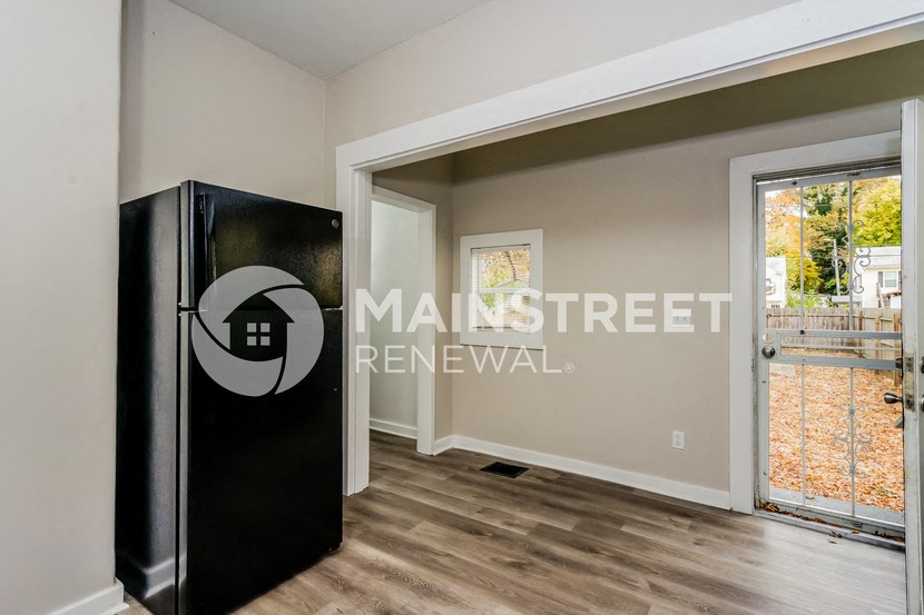 a living room with a refrigerator and a door to a balcony