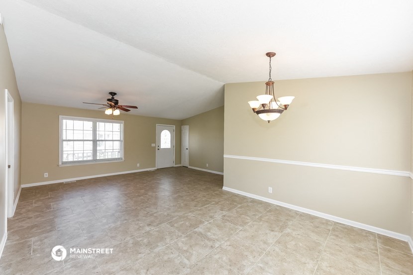 the spacious living room with beige walls and a ceiling fan