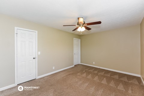 the spacious living room with ceiling fan and carpet
