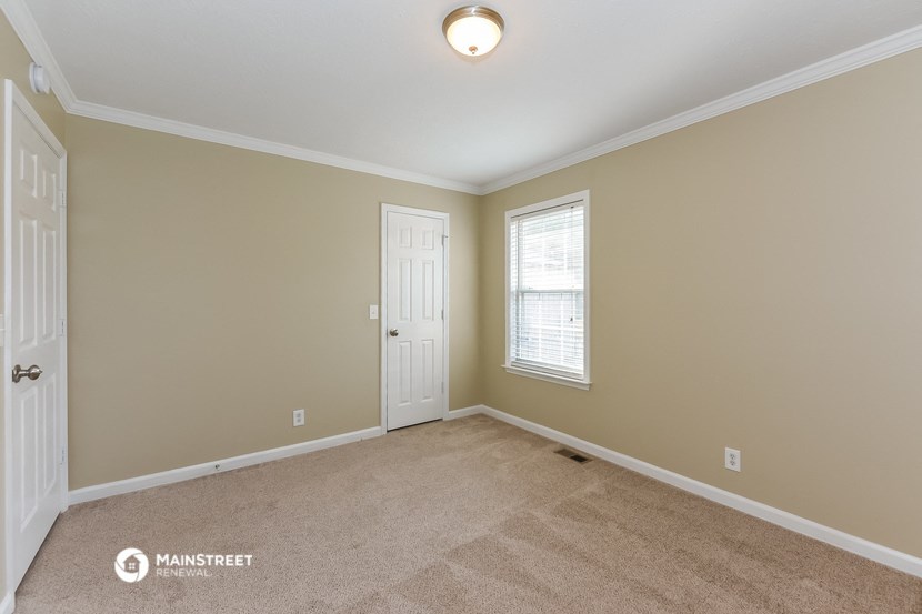 an empty room with a white door and a window