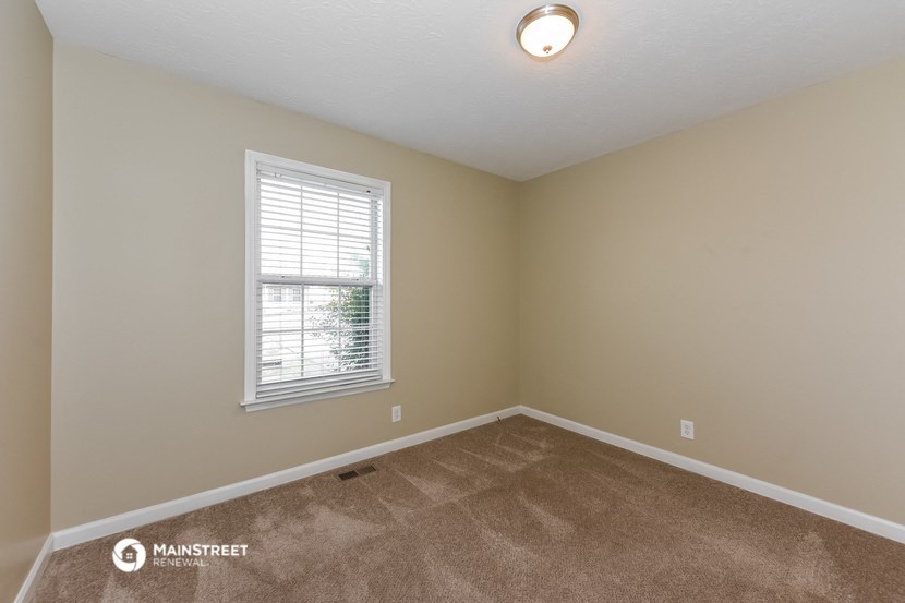 the spacious living room with carpet and a window