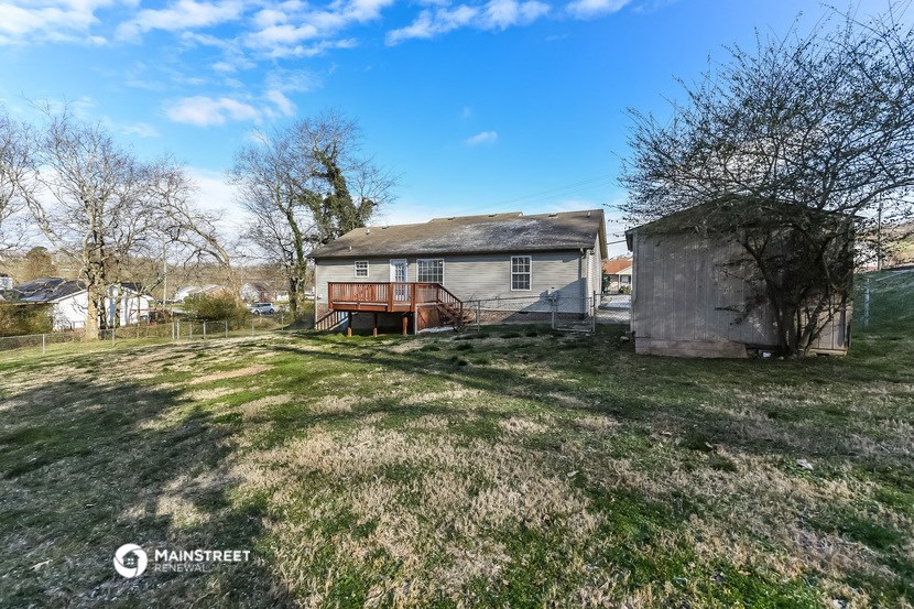 a small house with a deck in a grassy yard