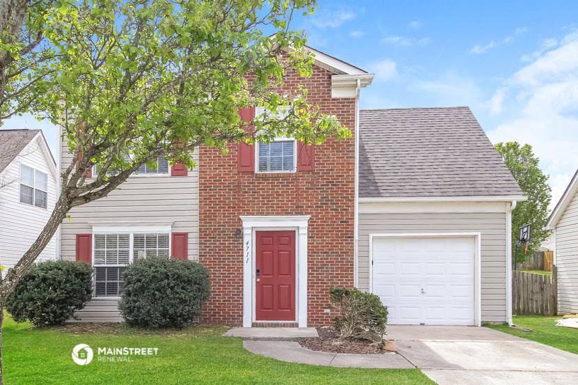 a house with a red door and a tree in front of it