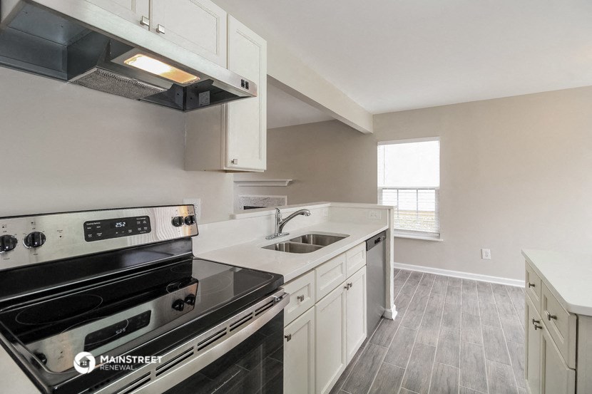 an empty kitchen with white cabinets and black appliances