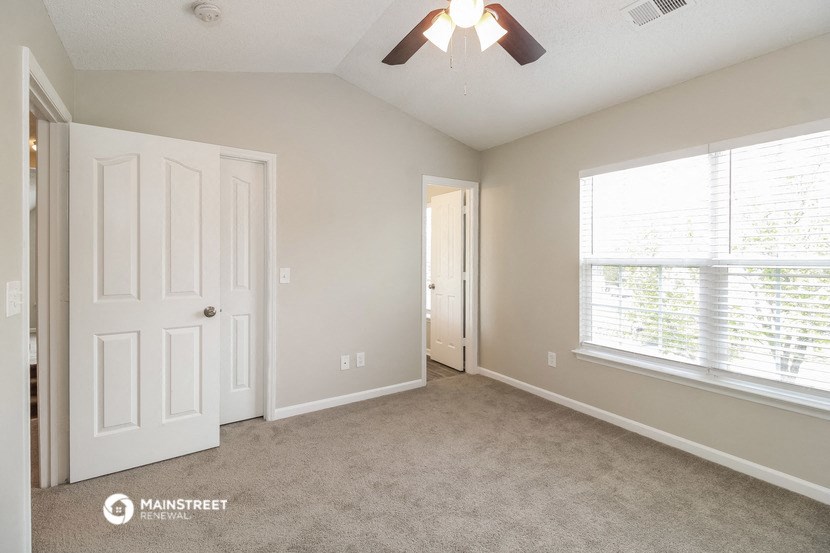 a bedroom with a ceiling fan and a large window