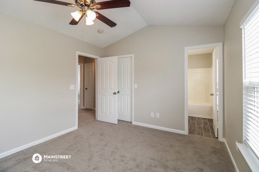 a bedroom with a ceiling fan and a door to a closet