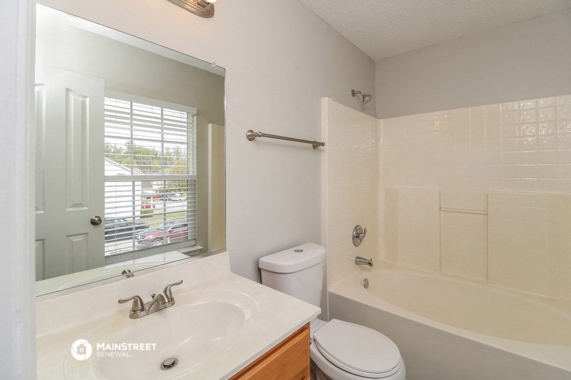 a white bathroom with a tub and a sink and a mirror