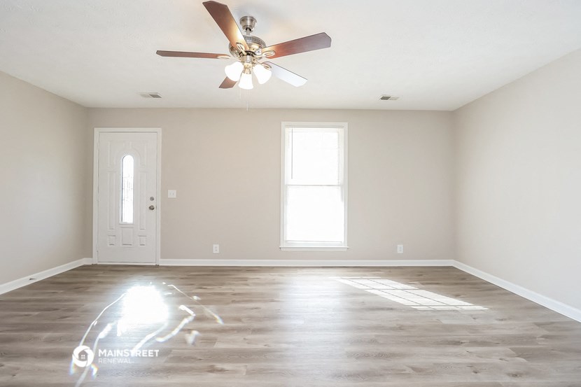 an empty living room with white walls and a ceiling fan