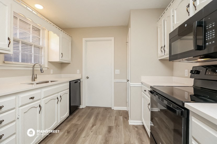 a renovated kitchen with white cabinets and black appliances