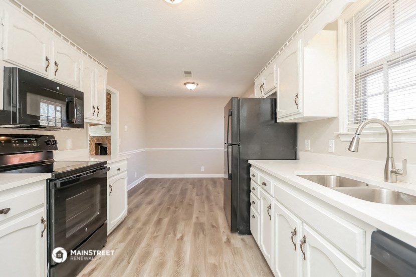 an empty kitchen with white cabinets and black appliances