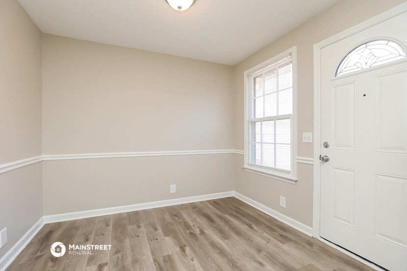 the spacious living room with hardwood flooring and a window