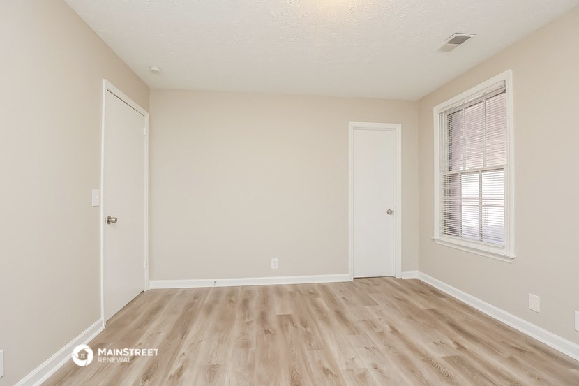 the spacious living room with wood flooring and white walls