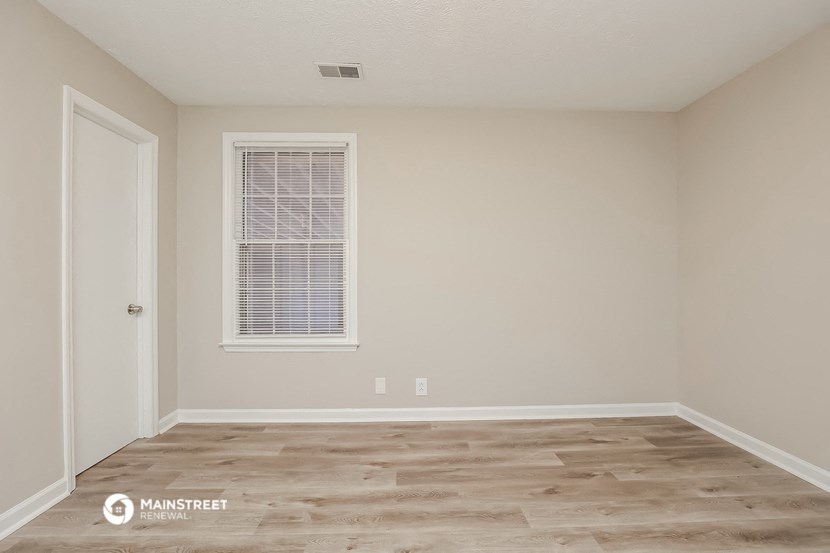 the spacious living room with a window and wood flooring
