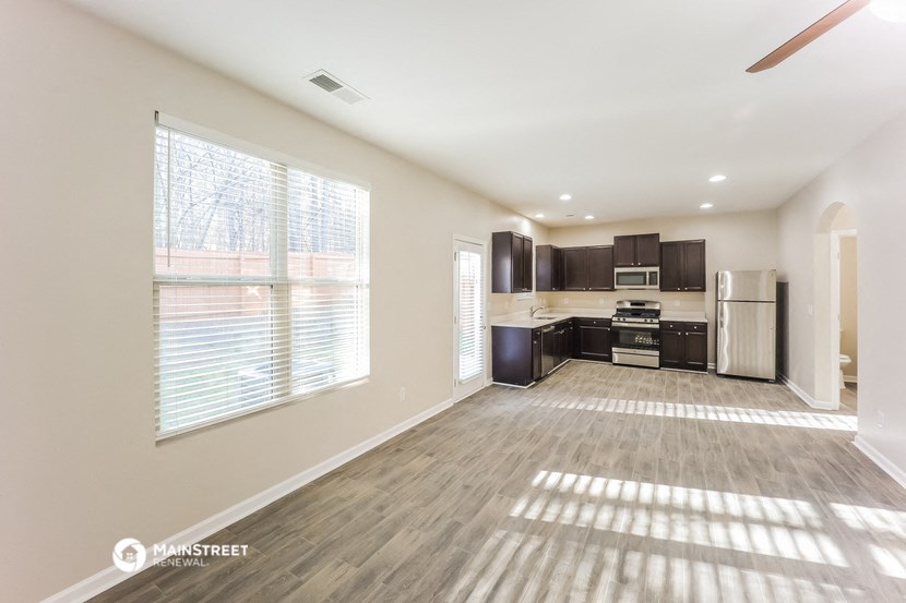 an empty living room and kitchen with a large window