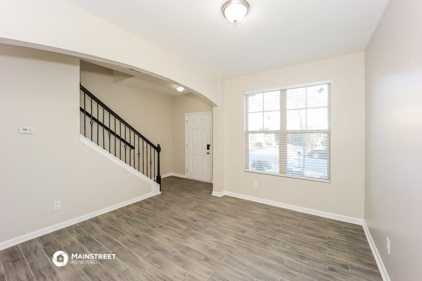 an empty living room with a staircase and a window