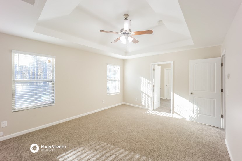 an empty living room with a ceiling fan and window
