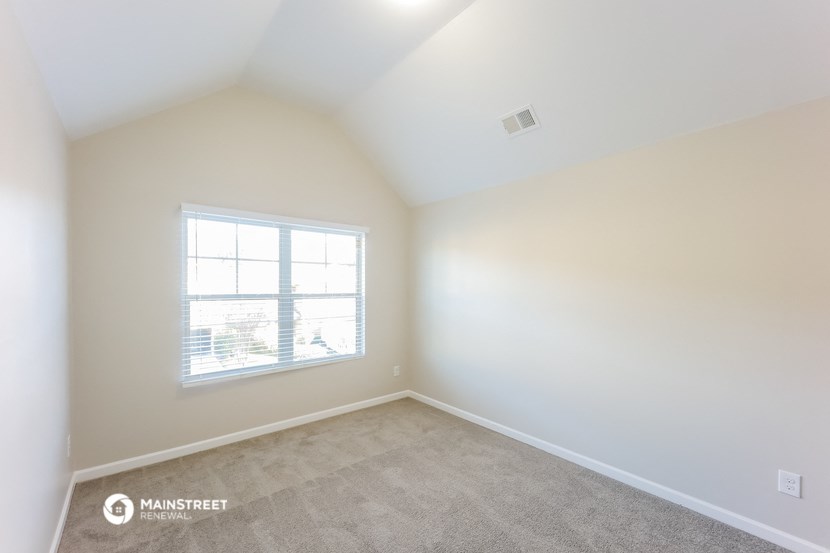 an empty room with a window and carpet