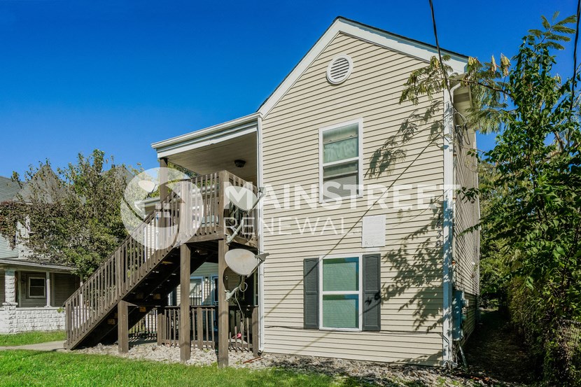 a side view of a house with a yard and stairs