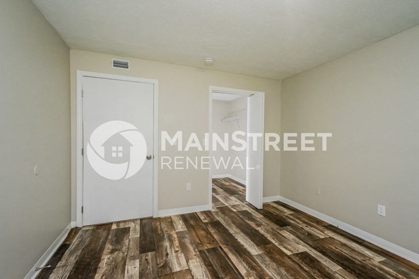 a bedroom with a door to a closet and a hard wood floor