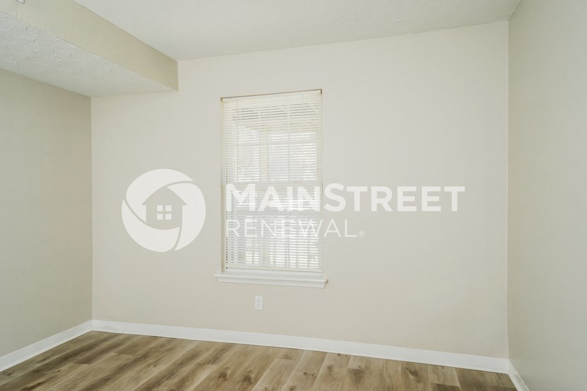 a bedroom with white walls and a window