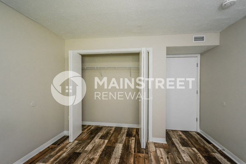 a walk in closet in a bedroom with wood floors and a closet door