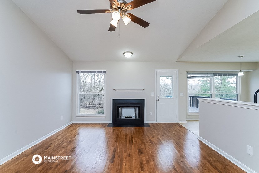 an empty living room with a fireplace and a ceiling fan