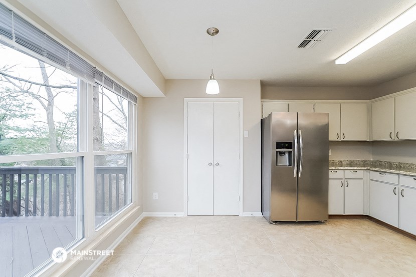 an empty kitchen with a large window and a stainless steel refrigerator