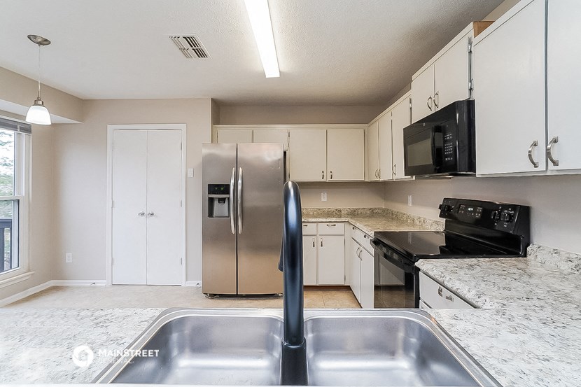 a kitchen with white cabinets and a stainless steel refrigerator