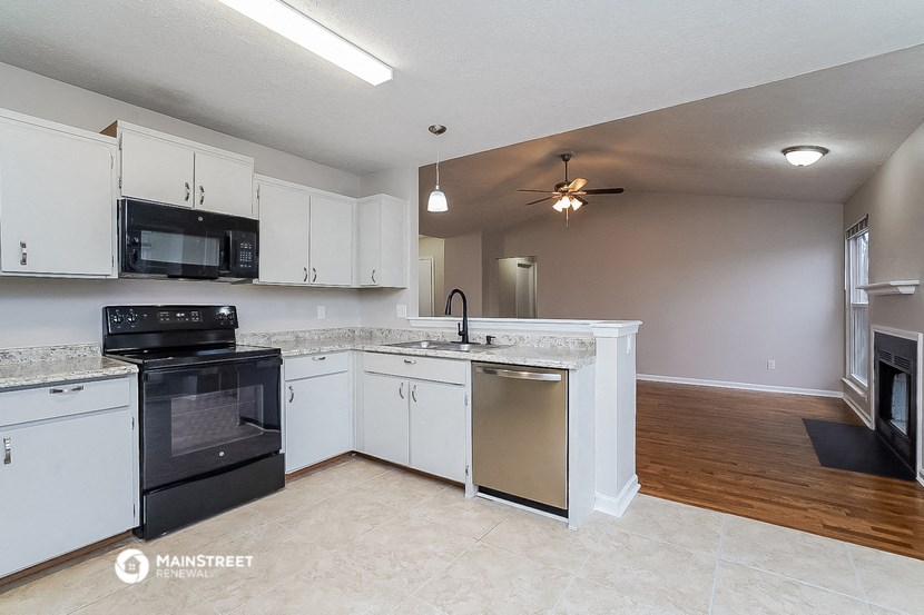 a kitchen with white cabinets and black appliances and a ceiling fan
