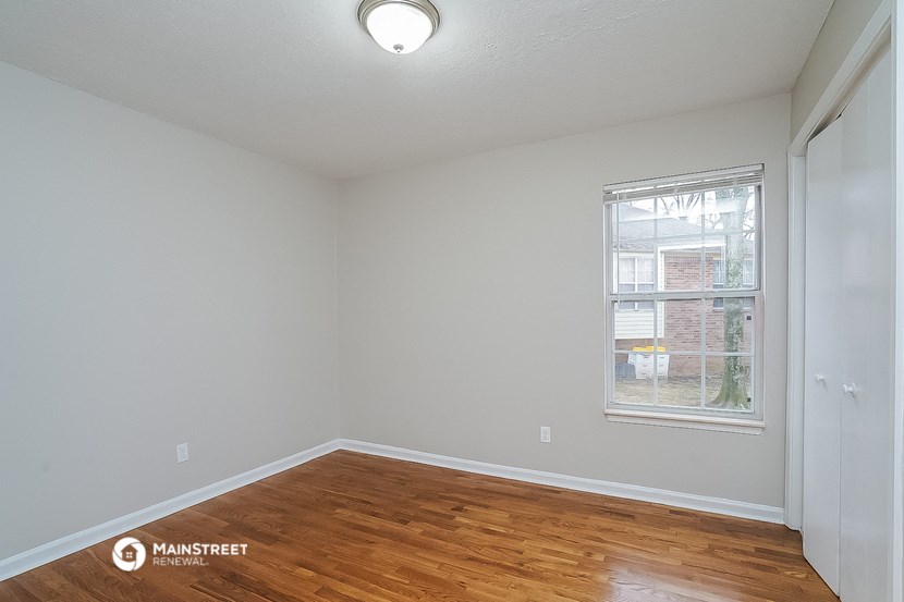 the spacious living room with wood flooring and a window