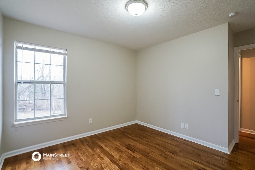 the spacious living room with hardwood flooring and a window