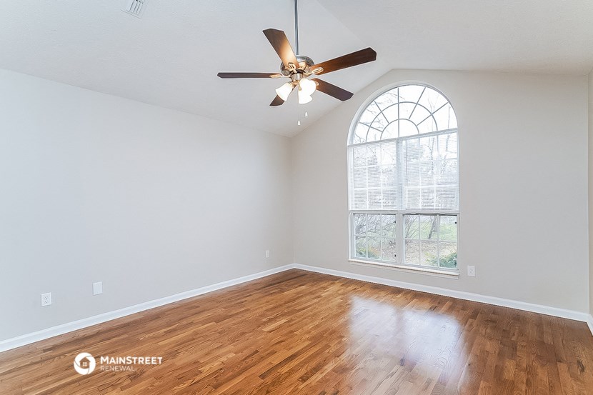 an empty living room with a ceiling fan and a window