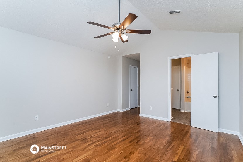 a living room with wood floors and a ceiling fan