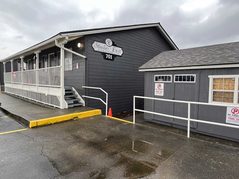 the front of a black building with a ramp and a porch
