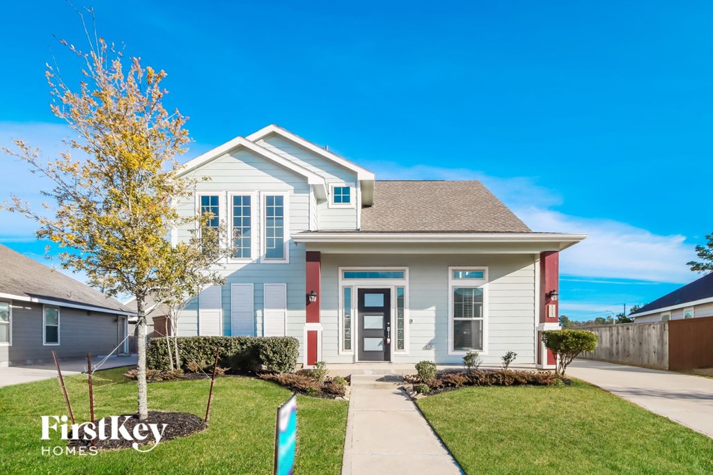 A house with a blue and white exterior and a red door is for sale by FirstKey Homes.