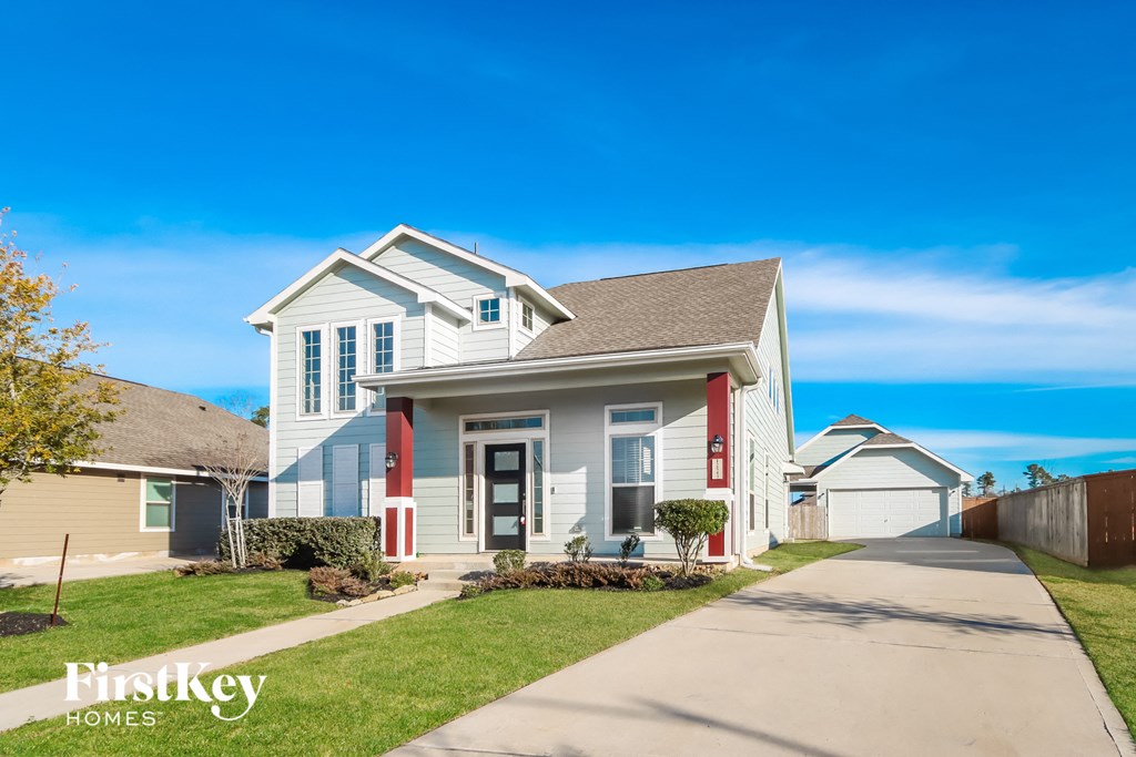 A white house with a red door and a sign that says "Firstkey Homes" in front of it.
