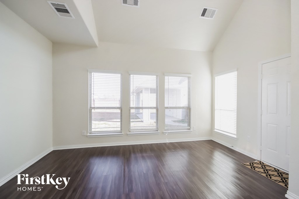 A room with wooden floors and a window with blinds.