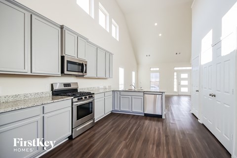 A kitchen with white cabinets and a wooden floor.
