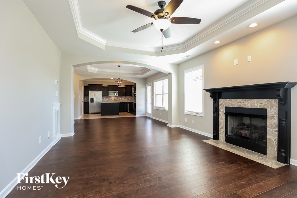 an empty living room with a fireplace and a ceiling fan