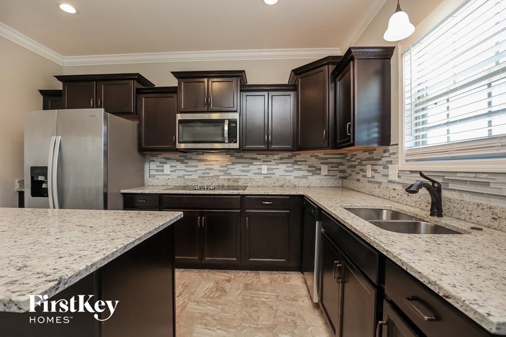a kitchen with dark cabinets and granite counter tops and a stainless steel refrigerator
