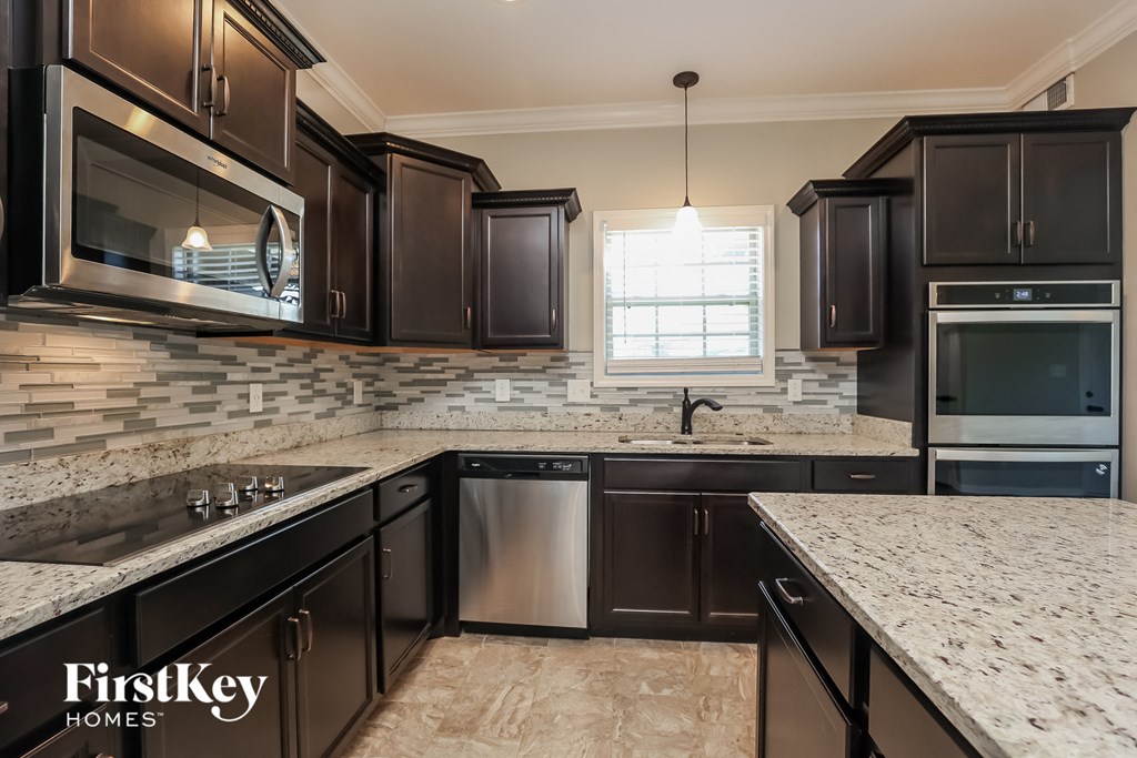 a kitchen with dark wood cabinets and marble counter tops and a sink