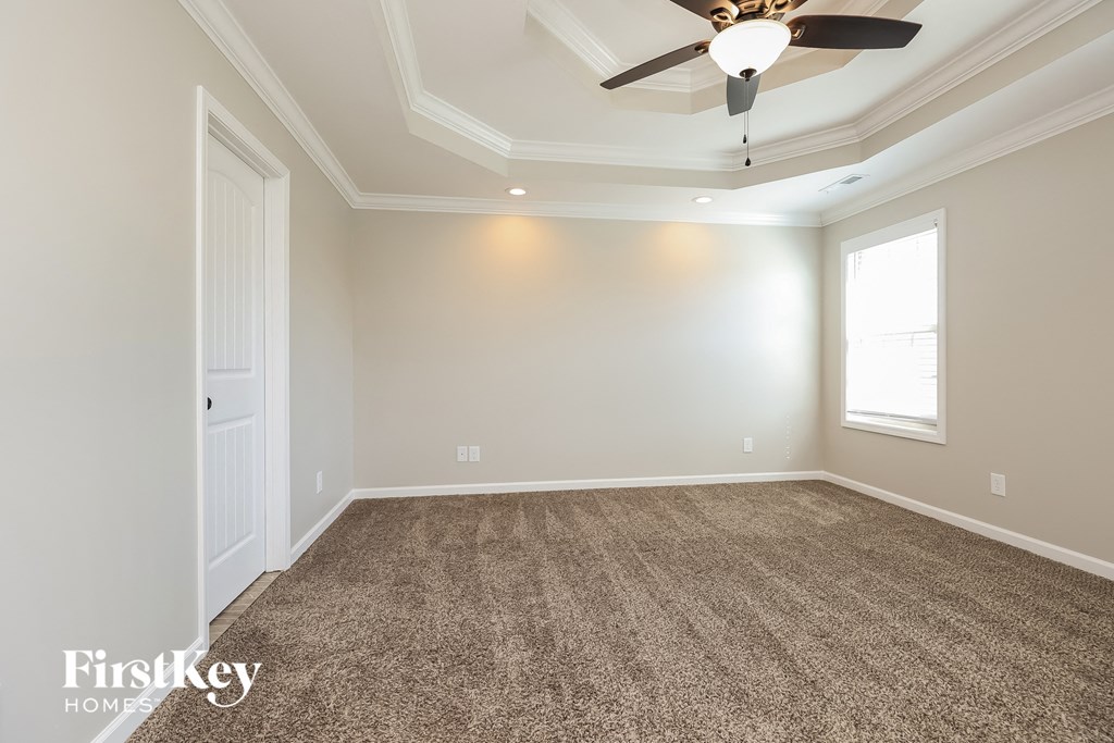 an empty living room with a ceiling fan and carpet