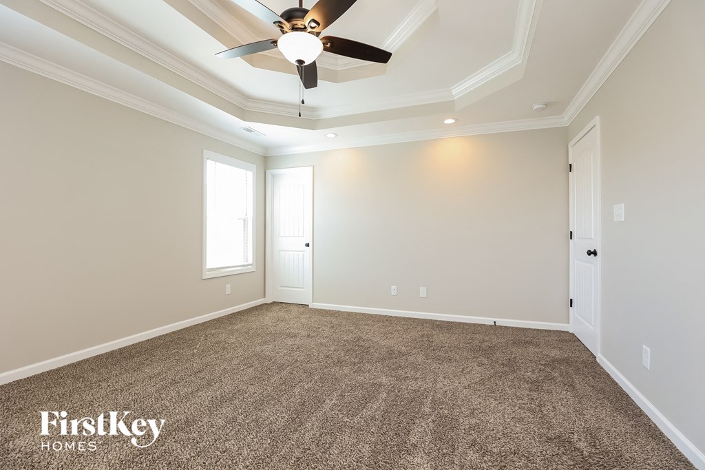 a empty living room with a ceiling fan and a carpet