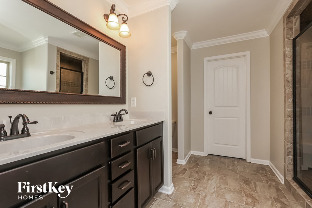 the master bathroom has a large vanity and a large mirror