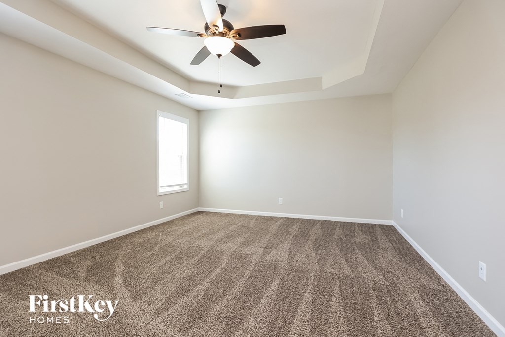 the spacious living room with ceiling fan and carpet